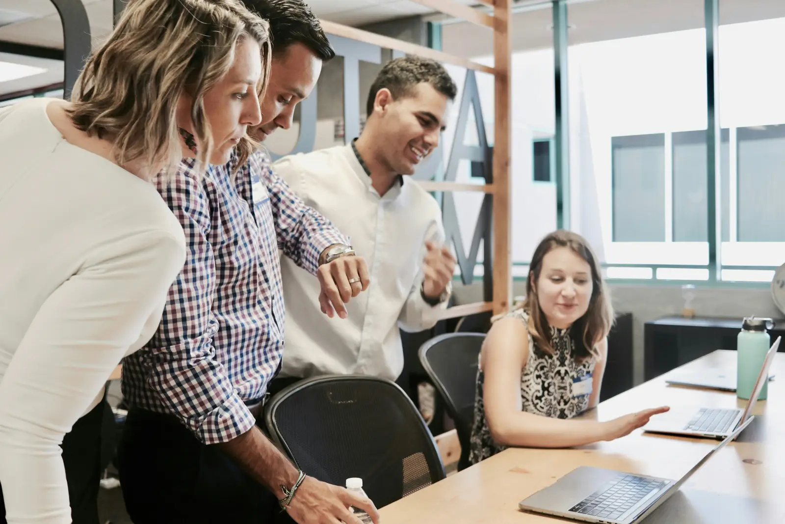 A colleague explaining something on a laptop to three teammates